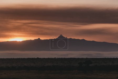 Fiery sunset silhouettes Monte Kenia sobre el paisaje brumoso