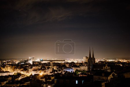 Vue nocturne de Marseille avec des clochers et des lumières de la ville.