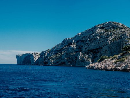 Sailboat cruising near towering limestone cliffs of the Calanques