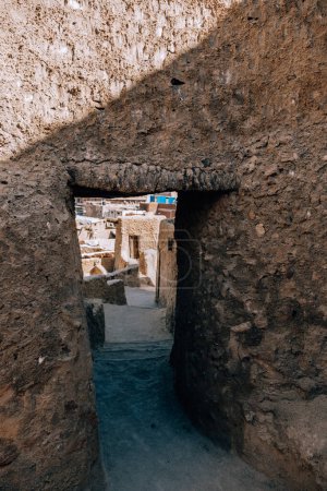 Torbogen aus Lehmziegeln in der Oase Siwa, Ägypten, mit Blick auf das Dorf