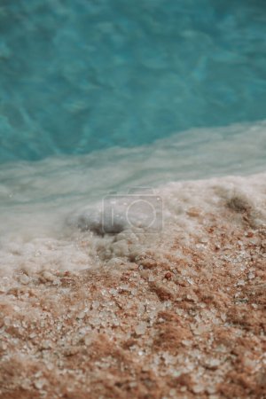 Close-up of crystalline salt deposits on the shore of a turquoise salt lake in Siwa Oasis, Egypt