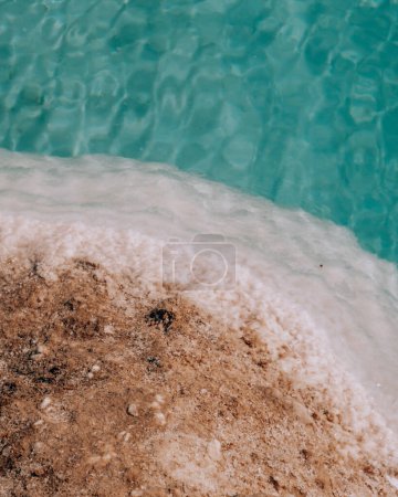 Nahaufnahme kristalliner Salzvorkommen am Ufer eines türkisfarbenen Salzsees in der Oase Siwa, Ägypten