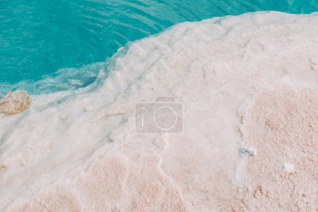Gros plan des dépôts de sel cristallin sur le rivage d'un lac salé turquoise dans l'oasis de Siwa, en Égypte