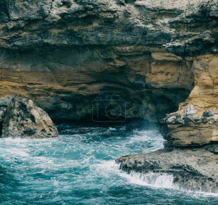 Rocky coastal cave with turquoise waters and rugged cliffs in Martinique, capturing the dramatic natural landscape of the Caribbean island