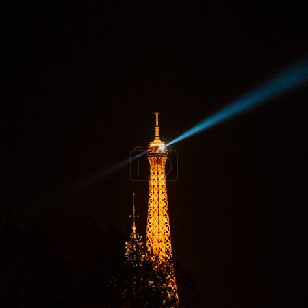 Illuminated Eiffel Tower with spotlight at night, Paris