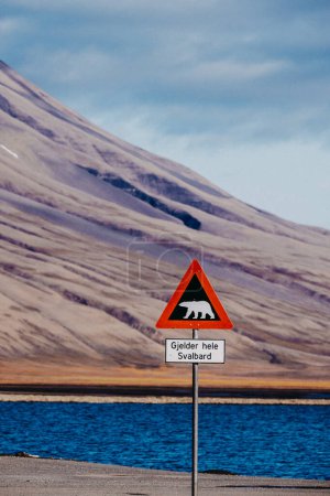 Señal de advertencia de oso polar contra telón de fondo montañoso en Longyearbyen, Svalbard