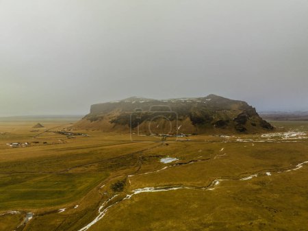 Panoramic aerial view of snow-dusted mountains and vast plains in South Iceland.