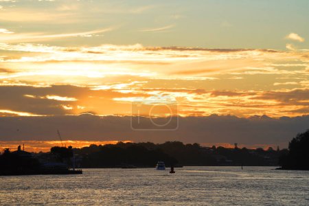 Hermosa puesta de sol sobre el puerto de Sydney, bandera aborigen australiana ondeando en el puente del puerto de Sydney, mirando hacia Goat Island y la entrada del río Parramatta desde Walsh Bay