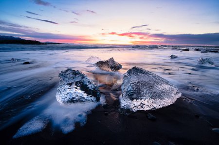 Eisschollen bei Sonnenaufgang mit spektakulären Farben am schwarzen Sand des Diamond Beach - Island