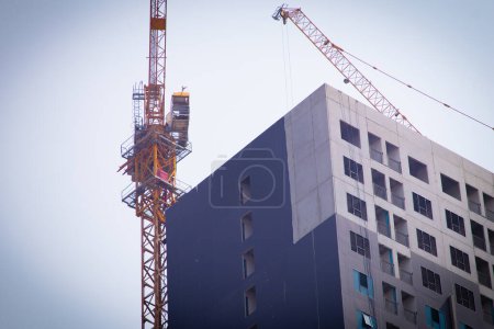 Photo for The tower crane installed at building and shows upper parts. - Royalty Free Image
