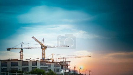 Téléchargez les photos : Environ 3 grues à tour installées sur un chantier de construction pour construire la ville et le ciel bleu - en image libre de droit