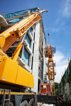 Installation eines Turmdrehkrans auf der Baustelle durch Einsatz eines Mobilkrans zum Heben und Montieren.