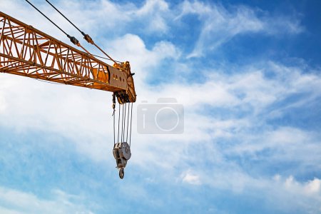 about the boom hoisting of crane at construction site and blue sky by emphasizing at boom crane detail and sling