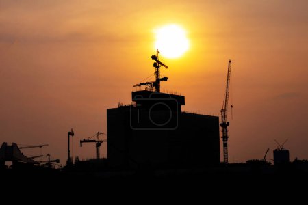 Photo for Those tower cranes were used to create built and in the picture, there was a construction site with sunset. - Royalty Free Image