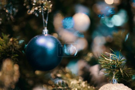 Decorated Christmas tree. Close-up of a blue bubble hanging from a decorated Christmas tree. The effect of the blurred background.