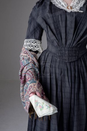 Una joven mujer victoriana con un vestido de algodón azul con ribete de encaje vintage en un fondo de estudio