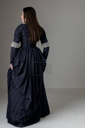 Une jeune femme victorienne portant une robe de coton bleu avec des garnitures de dentelle vintage sur fond de studio