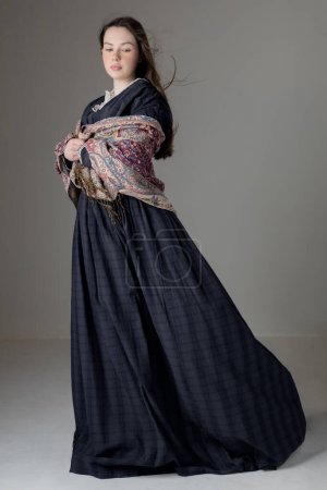 Photo pour Une jeune femme victorienne portant une robe de coton bleu avec des garnitures de dentelle vintage sur fond de studio - image libre de droit
