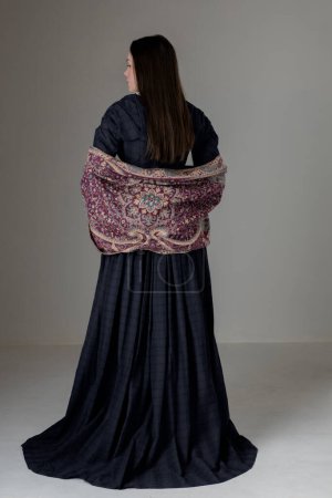 Eine junge viktorianische Frau trägt vor Studiokulisse ein blaues Baumwollkleid mit Spitzenbesatz
