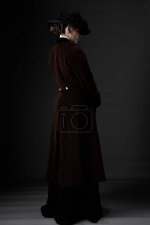 Mujer victoriana o eduardiana con abrigo y sombrero de invierno sobre un fondo de estudio