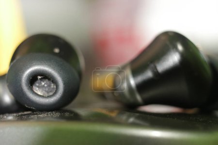 Close-up of black wireless earbuds with a blurred background.