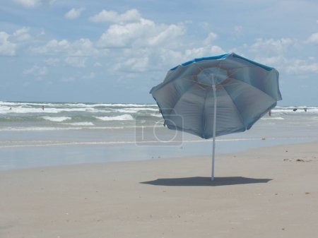 Un parapluie bleu solitaire dans le sable à New Smyrna Beach en Floride un jour ensoleillé du printemps