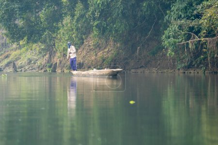 Téléchargez les photos : Un homme polissant une pirogue sur une rivière au Népal. - en image libre de droit