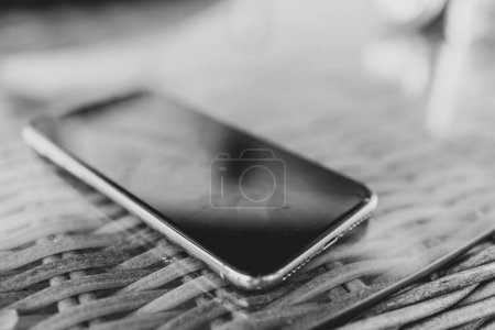 Macro shot of the corner of a smartphone on a glass table in black and white