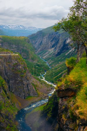 Paisaje de río en un arroyo rodeado de altas montañas con hierba. Voringfossen en Noruega.