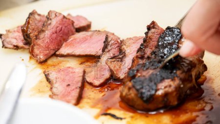 Une personne est méticuleusement trancher un steak magnifiquement cuit, révélant son centre tendre et rose. L'accent est mis sur la texture et la succulence de la viande, mettant l'accent sur l'habileté culinaire et les ingrédients de haute qualité.