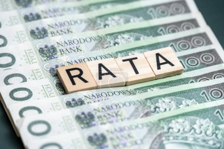 Detaillierte Nahaufnahme polnischer Banknoten mit hölzernen Buchstabenblöcken mit der Schreibweise "RATA", die ein Finanzkonzept im Zusammenhang mit Krediten oder Ratenzahlungen in Polen erfassen.