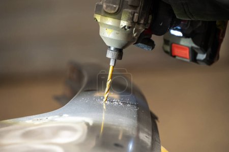 A close view of a drill in action, sparks flying as it pierces through a metallic motorcycle component, showcasing precision and craftsmanship in a workshop setting.