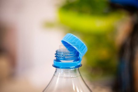 Une prise de vue ciblée capturant un capuchon en plastique bleu attaché sur une bouteille transparente, mettant l'accent sur la nouvelle réglementation européenne en vigueur à l'été 2024 visant à réduire la pollution.