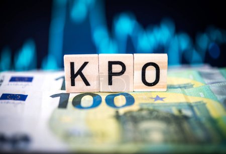 Close-up view of wooden alphabet cubes spelling 'KPO' atop a stack of Euro currency notes, highlighting themes of finance, investment and budgeting.