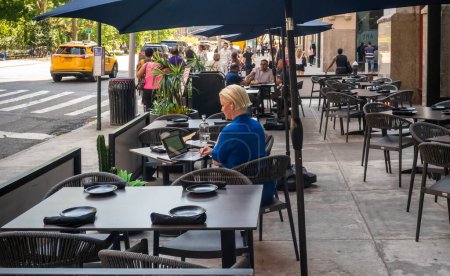 Foto de Nueva York, Estados Unidos-Mayo 21, 2024 Los comensales aprovechan el clima inusualmente cálido para hacer trabajo al aire libre y cenar en NoMad, Nueva York - Imagen libre de derechos