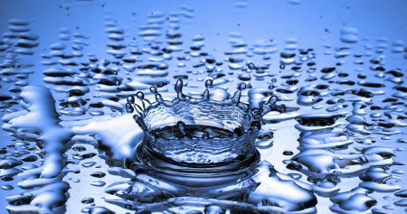 Téléchargez les photos : Goutte d'eau tombant dans l'eau sur fond bleu - en image libre de droit
