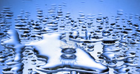 Téléchargez les photos : Goutte d'eau tombant dans l'eau sur fond bleu - en image libre de droit