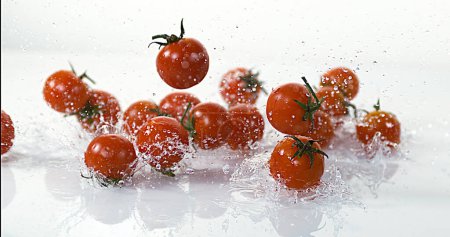 Foto de Tomates Cherry, Solanum lycopersicum, Frutas que caen al agua contra el fondo blanco - Imagen libre de derechos