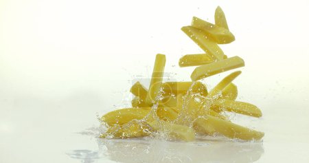 Photo for French Fries, Charlotte Potato, solanum tuberosum, Vegetable falling on Water against White Background - Royalty Free Image