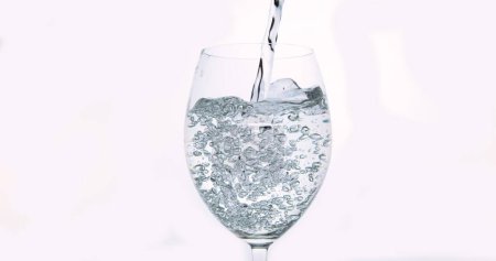 Foto de Agua que se vierte en vidrio contra fondo blanco - Imagen libre de derechos