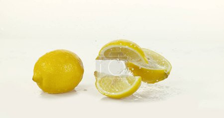 Téléchargez les photos : Citrons jaunes, limonum d'agrumes, fruits roulants sur l'eau et éclaboussures sur fond blanc - en image libre de droit
