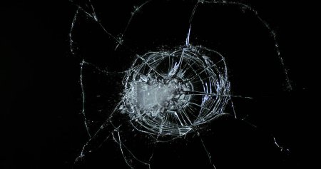 Photo for Golf Ball breaking Pane of Glass against Black Background - Royalty Free Image
