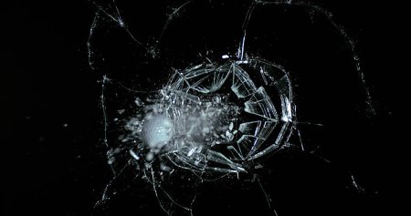 Photo for Golf Ball breaking Pane of Glass against Black Background - Royalty Free Image