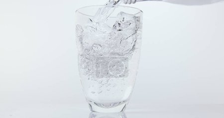 Foto de Agua que se vierte en vidrio contra fondo blanco - Imagen libre de derechos