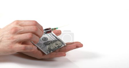 Photo for Syringe Falling into Hand with Dollars against White Background - Royalty Free Image