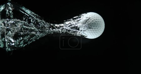 Téléchargez les photos : Balle de golf tombant dans l'eau sur fond noir - en image libre de droit