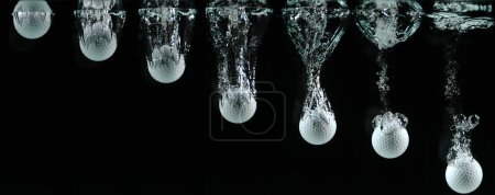 Photo for Golf's Ball Falling into Water against Black background. - Royalty Free Image