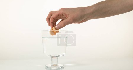 Foto de Tabletas cayendo en un vaso contra fondo blanco - Imagen libre de derechos