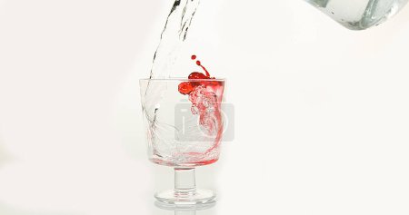 Foto de Agua que se vierte en vidrio contra fondo blanco, rojo en la parte inferior del vidrio - Imagen libre de derechos