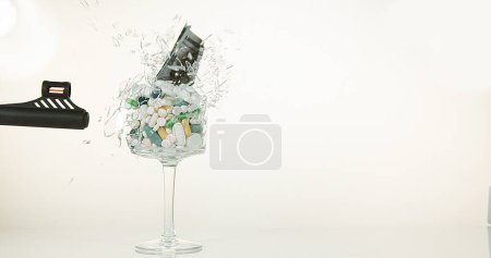 Photo for Glass filled with Capsules and Dollars Exploding against White Background - Royalty Free Image